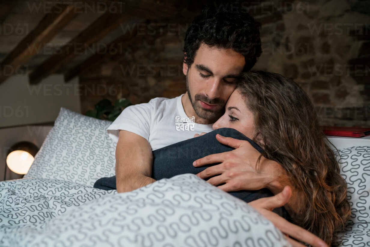 romantic couple lying in bed hugging CUF06826
